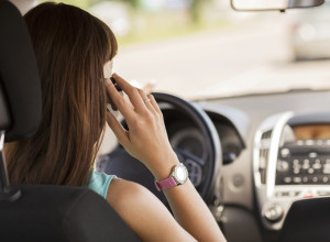 woman using phone while driving the car